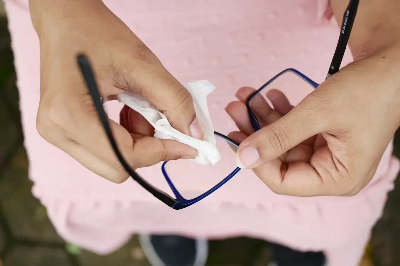 Nettoyage d’une paire de lunettes avec un chiffon doux, illustrant l’importance de l’entretien régulier pour préserver la qualité optique chez Regards Uniques